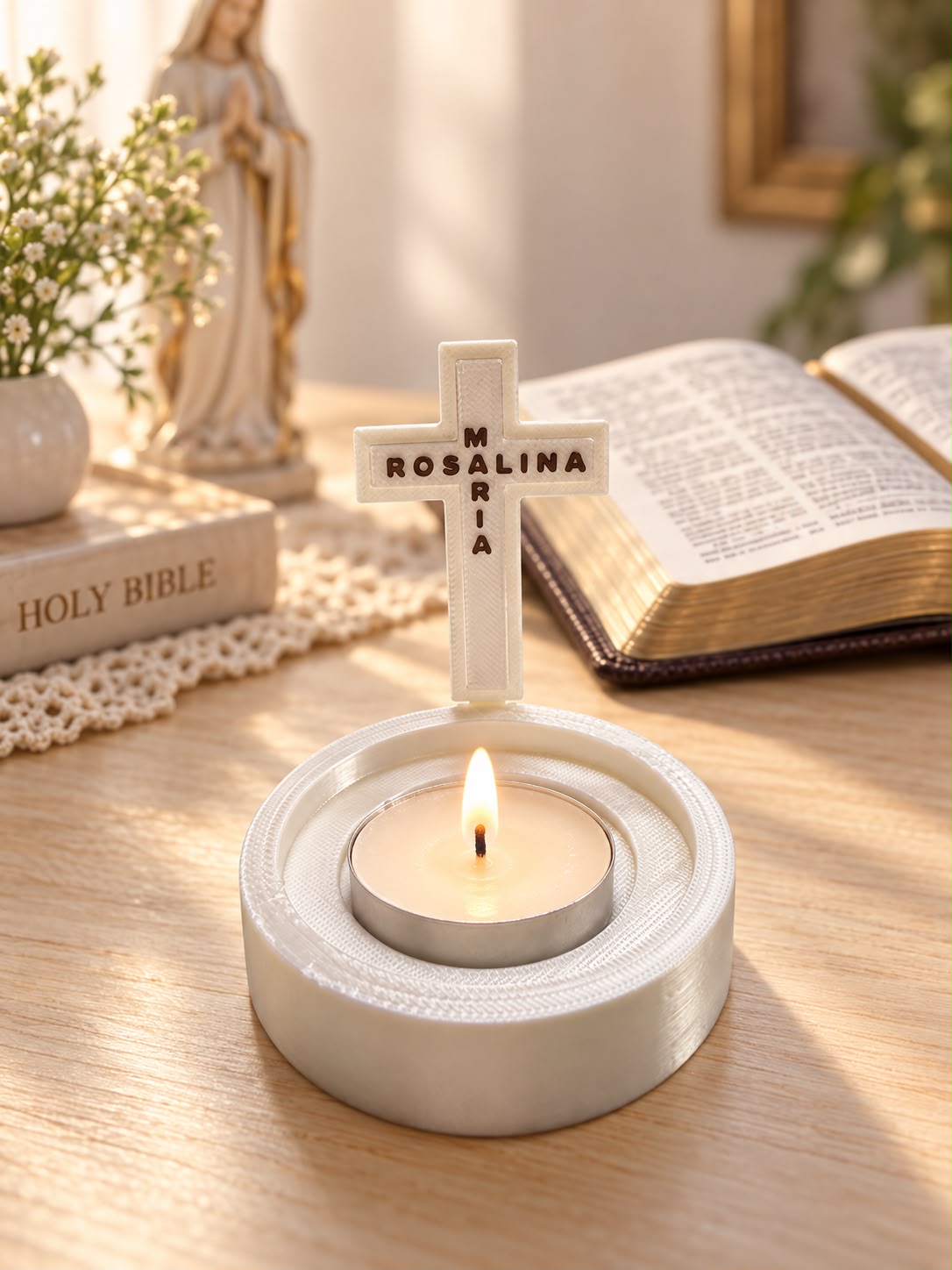 White personalized cross LED tea light holder with the names Maria and Rosalina on a wooden surface beside a Bible