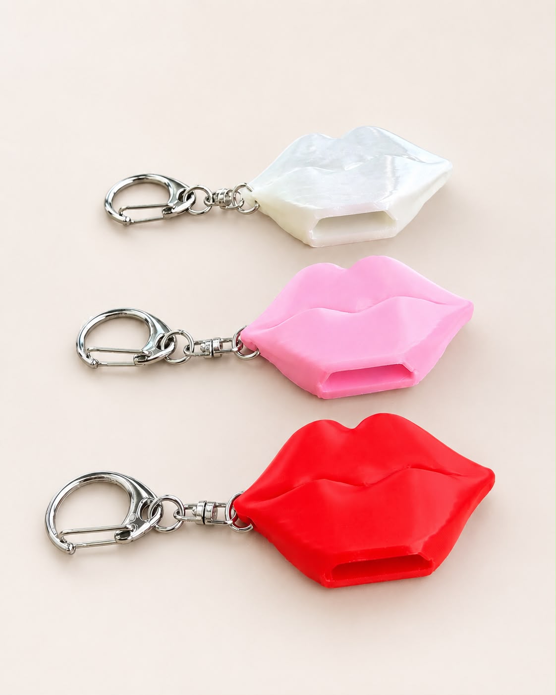 Three lip-shaped can opener keychains in pearl white, pink and red with silver clips