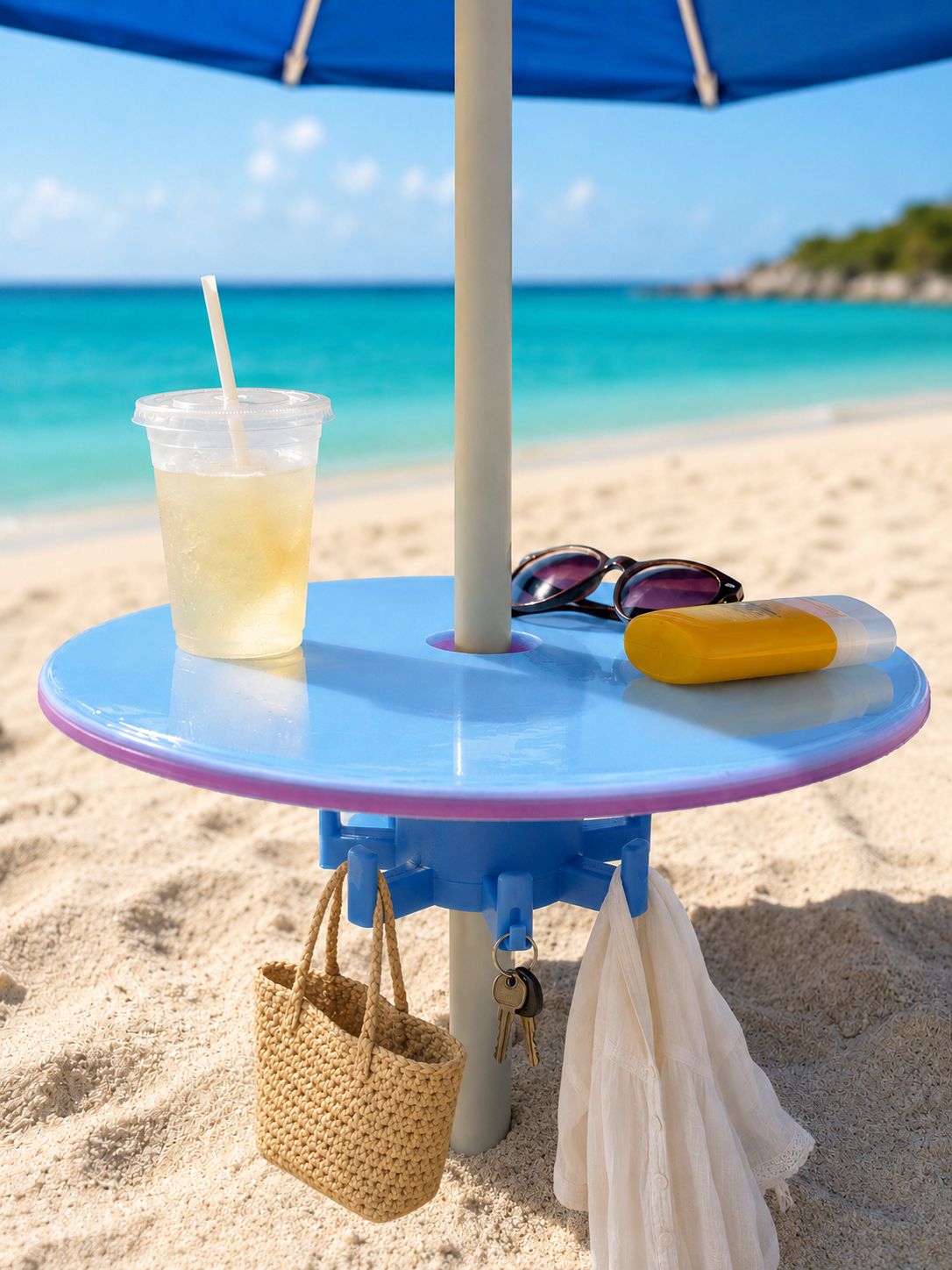 Blue holographic beach umbrella table with storage hooks holding a drink, sunglasses, sunscreen, bag and keys on a sandy beach